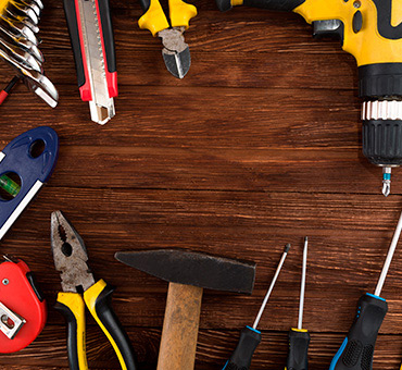 Foto de mesa de madera llena de herramientas como desarmadores, pinzas, cutters y taladros.