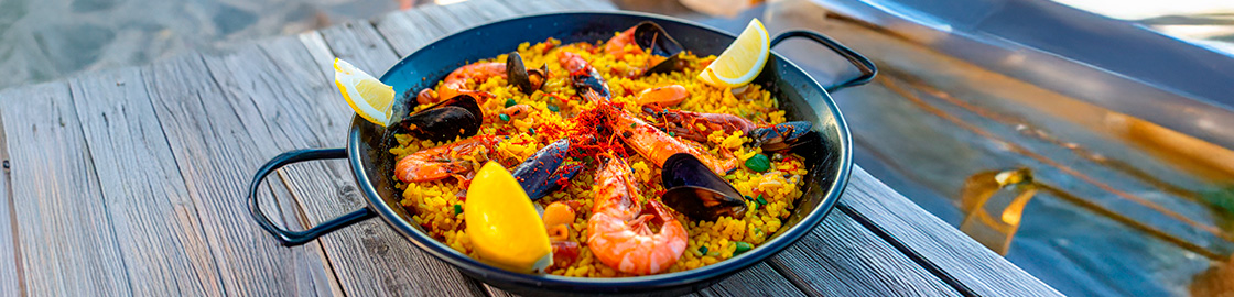 Foto de una paella de bonita presentación servida sobre una mesa de madera.