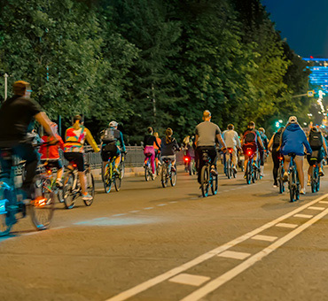 Foto de ciclistas rodando en una ciclovía urbana en la noche
