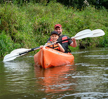 Foto de padre e hijo navegando un kayak en un río.