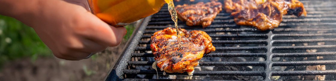 Foto de pollo a la parrilla al que le están vertiendo cerveza.