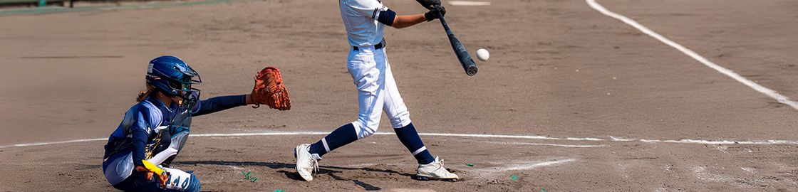 Foto de un joven en la caja de bateo, conectado un hit durante un juego de béisbol juvenil.